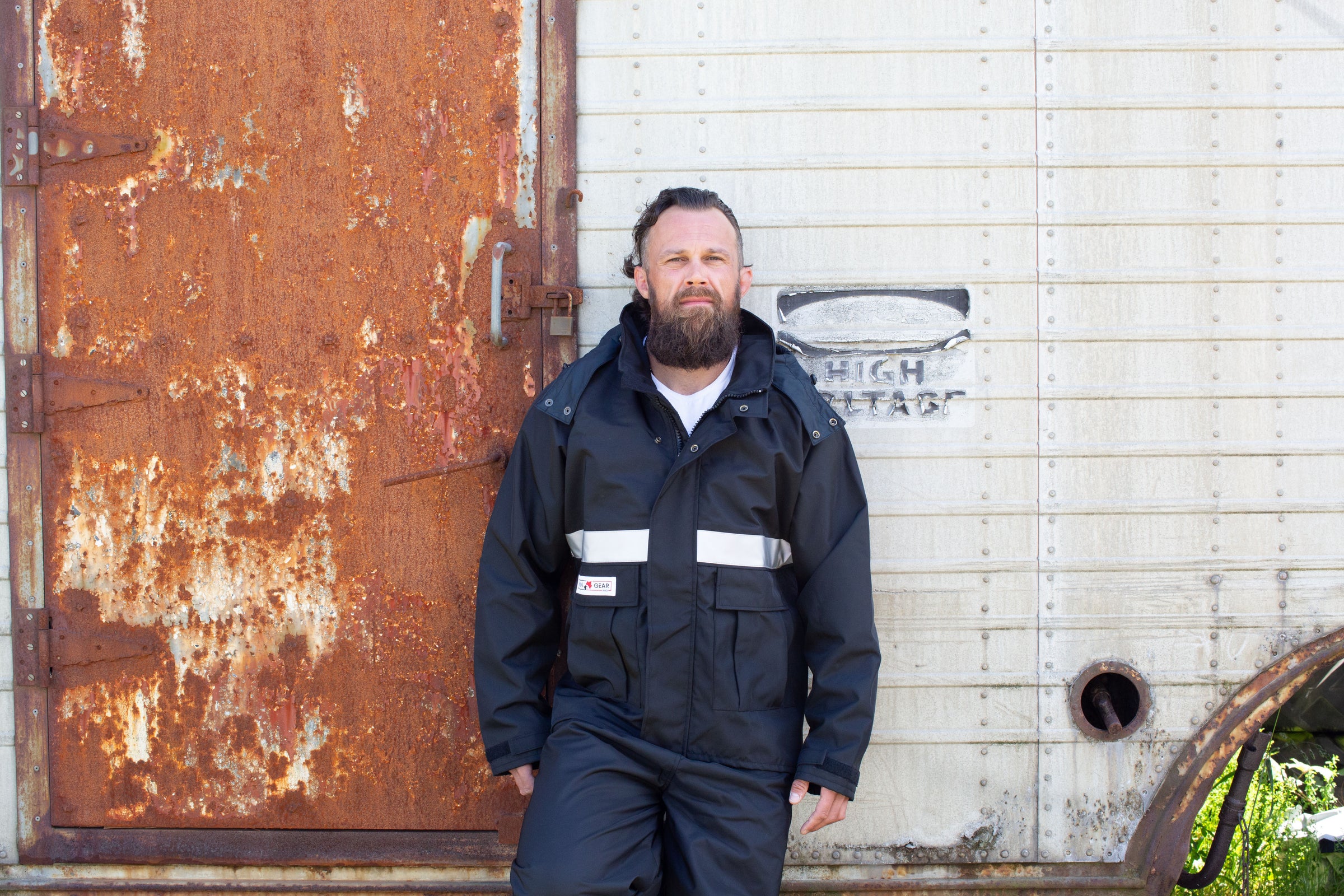 A worker in a Rain Gear Pro jacket by a weathered container
